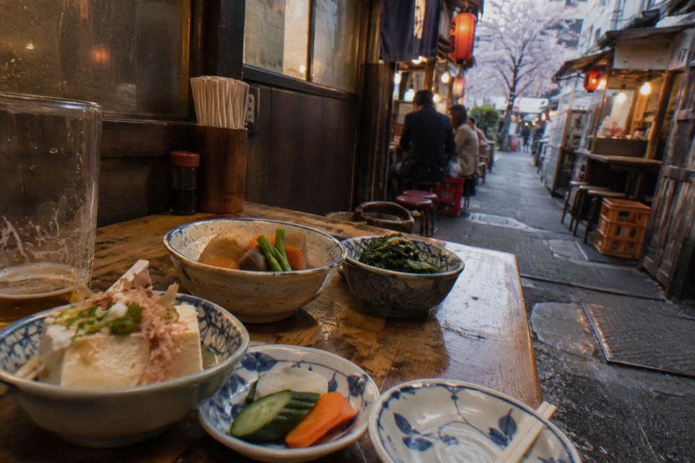 Assorted Japanese small dishes spread across a wooden izakaya table