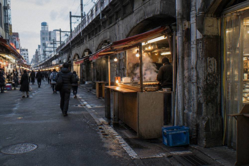 A glowing izakaya counter at night with lanterns hanging over a Tokyo side street